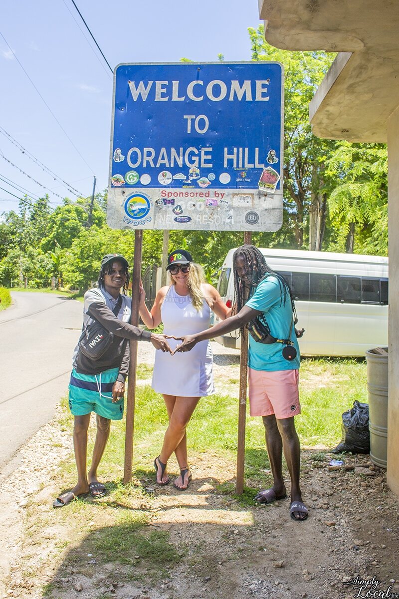 The Welcome to Orange Hill sign with local tour hosts