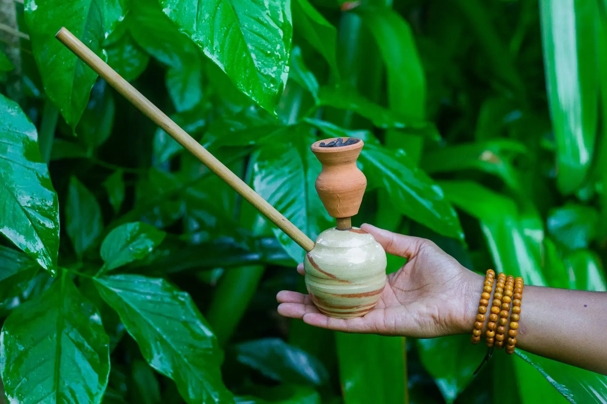 Authentic handmade Jamaican steam chalice held against tropical foliage