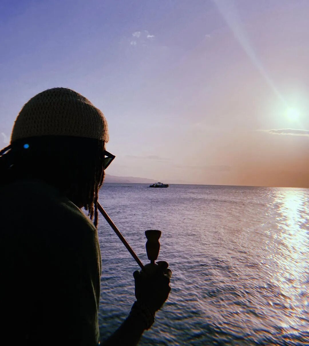 Rastafari steam-chalice use beside the sea at sunset